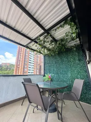 a table and chairs on a balcony with a green wall at Habitación en apto duplex baño compartido, piso 5 sin ascensor in Envigado