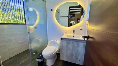 a bathroom with a toilet and a sink and a mirror at Rooca Habitat Guatape in Guatapé