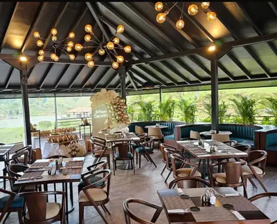 a restaurant with wooden tables and chairs and a chandelier at Rooca Habitat Guatape in Guatapé