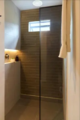 a shower with a glass door in a bathroom at Cozy Aparta-Suite Stadio Rosa Negra in Medellín