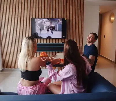 a group of people sitting on a couch watching a tv at Comfy Aparta-Suite Stadio Rosa Negra in Medellín