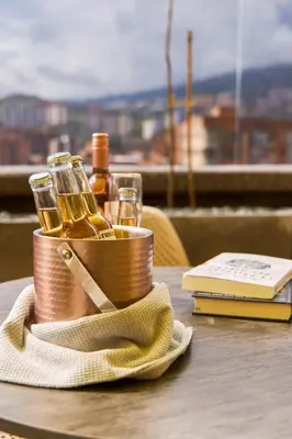 a table with a basket of wine glasses and a book at Comfy Aparta-Suite Stadio Rosa Negra in Medellín