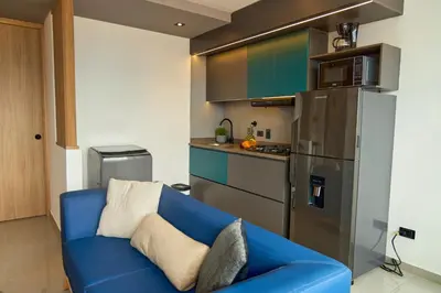 a blue couch in a kitchen with a refrigerator at Cozy Aparta-Suite Stadio Jacuzzi Rosa Negra in Medellín