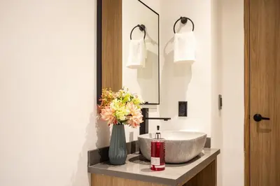 a bathroom with a sink and a vase of flowers at Comfortable Stadio Suite Rosa Negra in Medellín