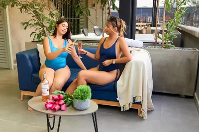 two women in bathing suits sitting on a couch at Comfortable Stadio Suite Rosa Negra in Medellín