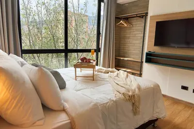a bedroom with a white bed and a large window at Rosa Negra Comfort Stadio Aparta-Suite in Medellín