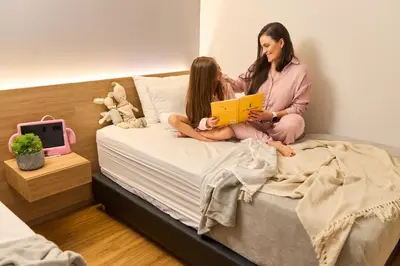 a woman and child sitting on a bed reading a book at Rosa Negra Comfort Stadio Aparta-Suite in Medellín