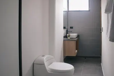 a white bathroom with a toilet and a sink at Stadio Serenity Rosa Negra Aparta-Suite in Medellín