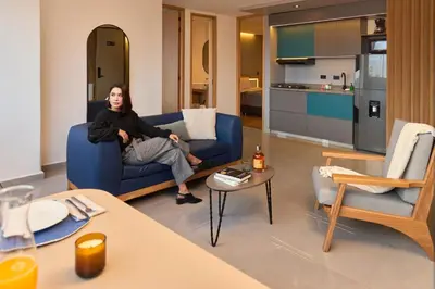 a man sitting on a blue couch in a living room at Elegant Cozy Suite Rosa Negra Stadio in Medellín