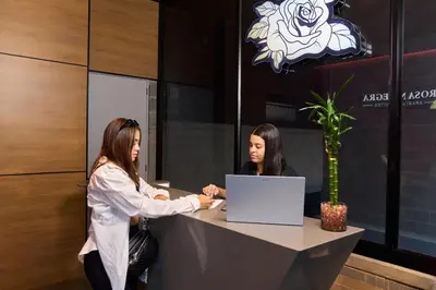 two women shaking hands at a desk with a laptop at Elegant Cozy Suite Rosa Negra Stadio in Medellín