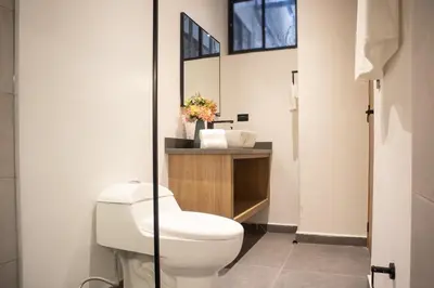 a bathroom with a white toilet and a mirror at Jacuzzi Retreat Cozy Aparta-Suite Rosa Negra in Medellín