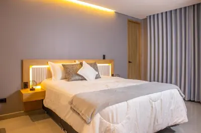 a bedroom with a large white bed with pillows at Chic and Cozy Stadio Suite Rosa Negra in Medellín
