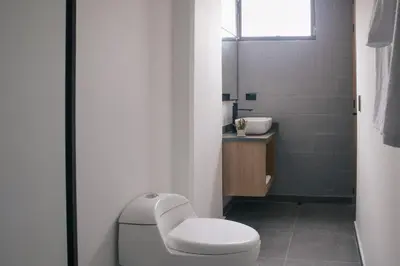 a white bathroom with a toilet and a sink at Chic and Cozy Stadio Suite Rosa Negra in Medellín