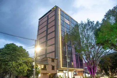 a tall building on a city street with trees at Chic and Cozy Stadio Suite Rosa Negra in Medellín