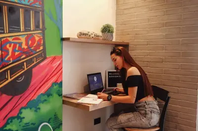 a woman sitting at a desk with a laptop at Chic and Cozy Stadio Suite Rosa Negra in Medellín