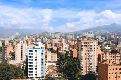 a city with tall buildings and mountains in the background at Rosa Negra's Cozy Stadio Haven in Medellín