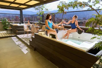two women in bathing suits sitting in a bath tub on a building at Rosa Negra's Cozy Stadio Haven in Medellín