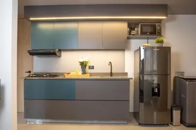 a kitchen with blue cabinets and a stainless steel refrigerator at Stadio Serenity Suite | Rosa Negra in Medellín
