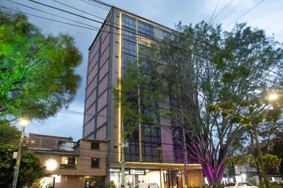 a tall glass building with trees in front of it at Stadio Serenity Suite | Rosa Negra in Medellín