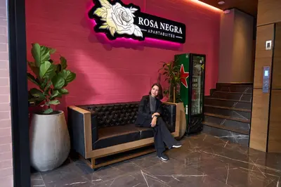 a woman sitting on a bench in front of a building at Cozy Getaway | Rosa Negra Stadio Suite in Medellín