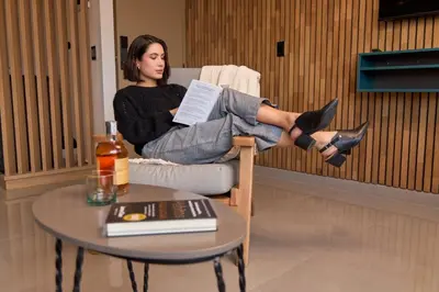 a woman sitting in a chair reading a book at Cozy Getaway | Rosa Negra Stadio Suite in Medellín