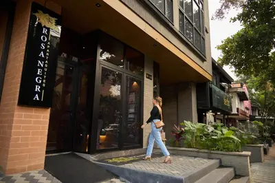 a woman walking in front of a store at Warm and Cozy Stadio Suite Rosa Negra in Medellín