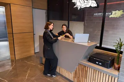 two women standing at a counter with a laptop at Warm and Cozy Stadio Suite Rosa Negra in Medellín