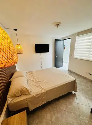 a bedroom with a bed and a flat screen tv at Hermoso y amplio apartamento cerca al centro de Medellin in Medellín