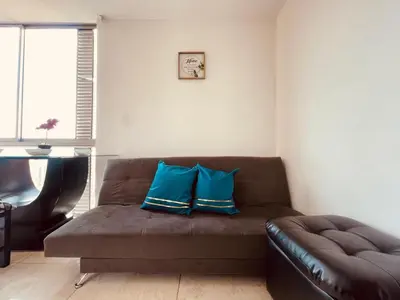 a living room with a brown couch with blue pillows at Mejor alojamiento cerca Provenza 191 in Medellín