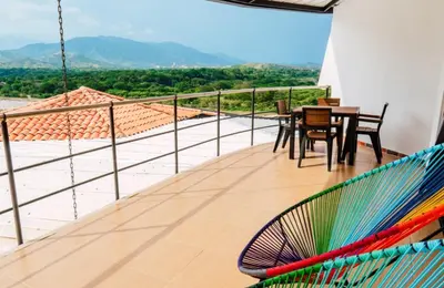 a balcony with a hammock and a table and chairs at Casa Hotel Cautiva in Sopetran