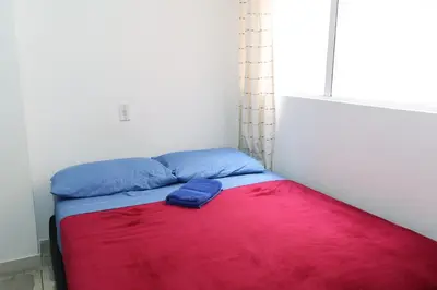 a bed in a room with a red and blue blanket at Living Poblado Manila 3020 Habitación Doble in Medellín
