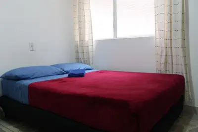 a bedroom with a bed with a red blanket and a window at Living Poblado Manila 3028 Habitación Doble in Medellín
