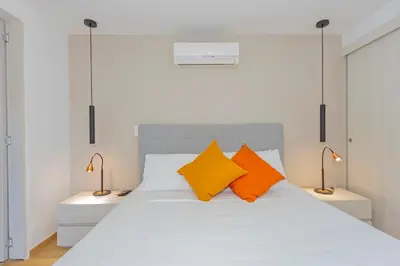 a bedroom with a white bed with two orange pillows at Alcazar de oviedo by Host Medellin in Medellín
