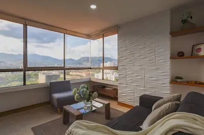 a living room with a couch and a large window at Alcazar de oviedo by Host Medellin in Medellín