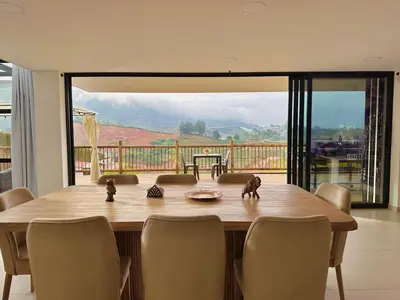 a dining room table with chairs and a large window at Casa Fénix in Marinilla