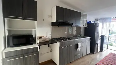 a kitchen with gray cabinets and a black refrigerator at Lindos Apartamentos con Terraza in Manizales
