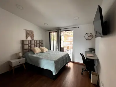 a bedroom with a bed and a desk and a window at Lindos Apartamentos con Terraza in Manizales