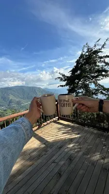 a person holding a cup of coffee on a deck at Casa Tikkun in Medellín
