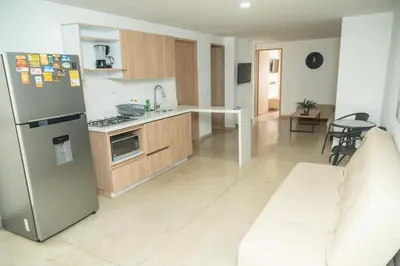 a kitchen with a stainless steel refrigerator and a couch at Apartamentos Montecarlo in Medellín