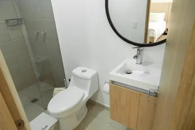 a bathroom with a toilet and a sink and a mirror at Apartamentos Montecarlo in Medellín