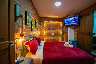 a bedroom with a red bed with a doll on it at Hotel Spa Bliss Guatape in Guatapé