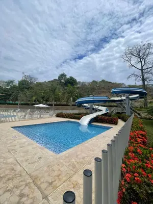 a swimming pool with two umbrellas and flowers at Luxury Apartment Citadela de Sole Santa fe de Antioquia in Santa Fe de Antioquia