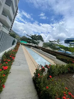 a swimming pool with flowers next to a building at Luxury Apartment Citadela de Sole Santa fe de Antioquia in Santa Fe de Antioquia