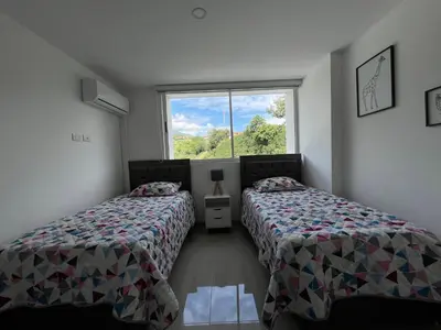 two beds in a room with a window at Luxury Apartment Citadela de Sole Santa fe de Antioquia in Santa Fe de Antioquia