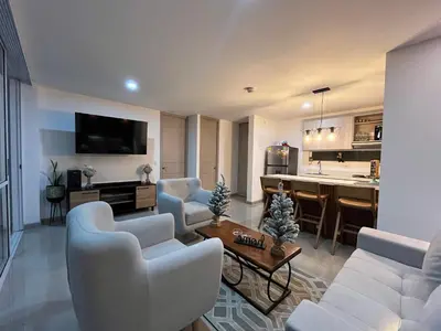 a living room with white furniture and a kitchen at Luxury Apartment Citadela de Sole Santa fe de Antioquia in Santa Fe de Antioquia