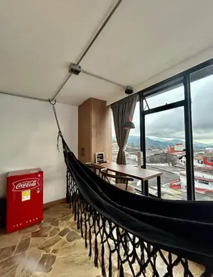 a hammock in a room with a table and window at Open Sky in Manizales