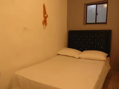 a bedroom with a bed with two pillows and a window at Hospedaje J&L in Medellín