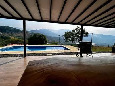 a view of a swimming pool with a table and a piano at Finca cerca a Medellín Villa Cerat in Sopetran