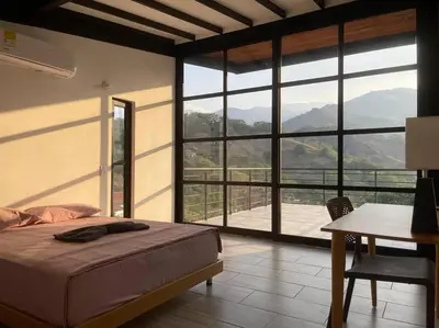 a bedroom with a bed and a desk and a large window at Finca cerca a Medellín Villa Cerat in Sopetran