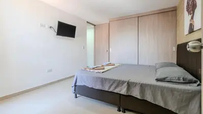 a bedroom with a large bed and a tv at Apartamento en Laureles con piscina y parquedero 802 in Medellín